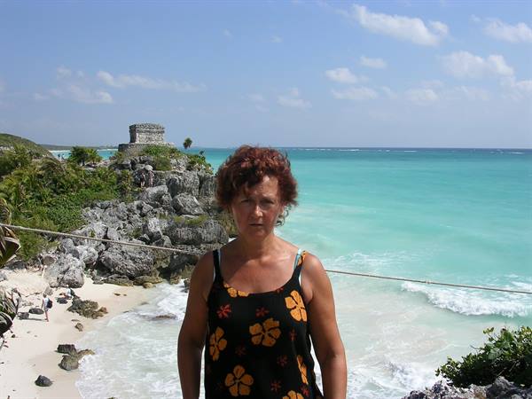 Red-haired woman in front of the Mayan ruins of Tulum on the Caribbean Sea