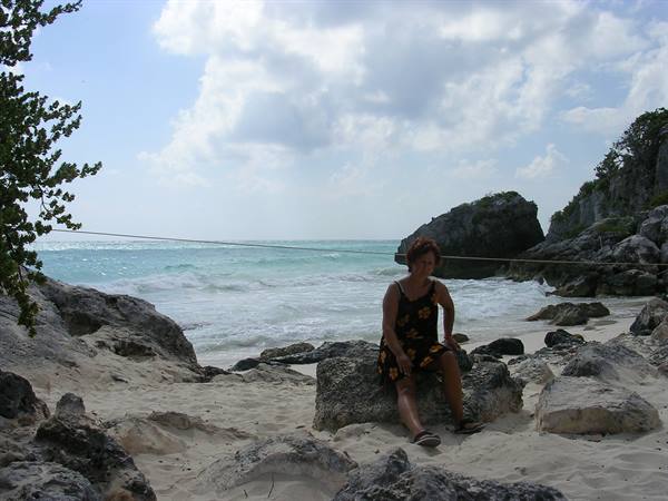 Woman sitting on a limestone rock at Tulum beach, turquoise sea