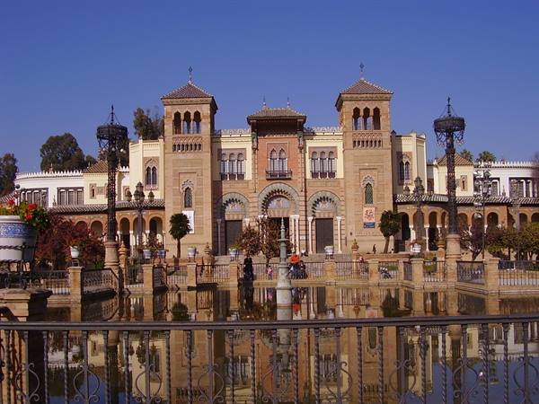 Mudéjar Pavilion at María Luisa Park, Seville, reflecting in the pond under blue sky
