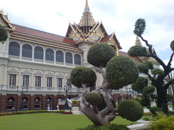 Grand Palace facade in Bangkok with topiary trees, morning light