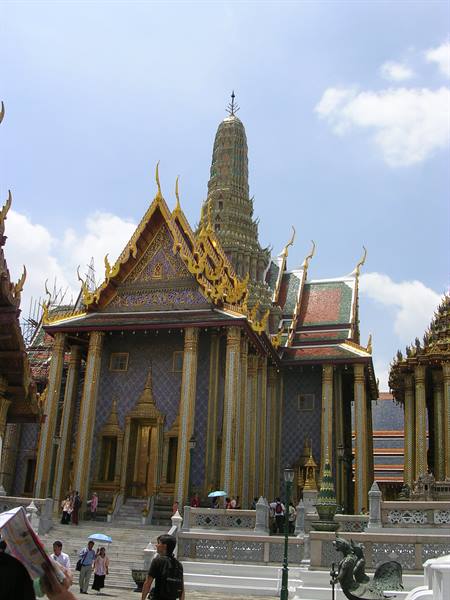 Tourists with umbrellas in front of the golden Wat Phra Kaew temple, Bangkok