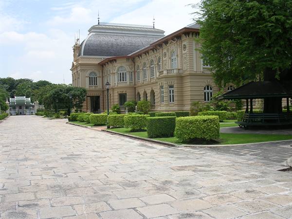 Pale stone colonial palace with manicured gardens and stone-paved walkway
