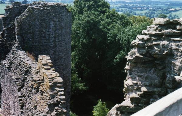 Stone castle ruins wall overlooking trees and green countryside