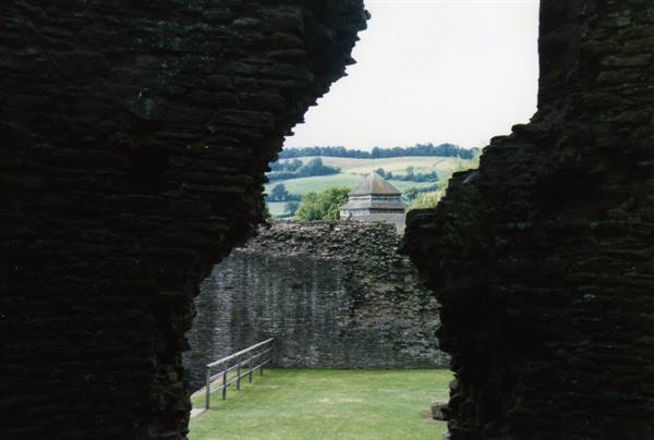 Weathered stone castle walls, octagonal tower and green hills beyond