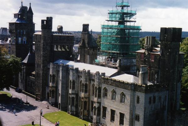 Cardiff Castle stone towers and green scaffolding under cloudy sky