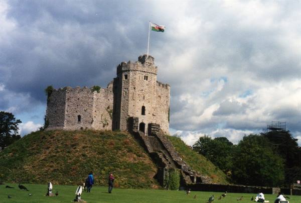 Norman stone keep of Cardiff Castle on grassy mound, Welsh flag flying