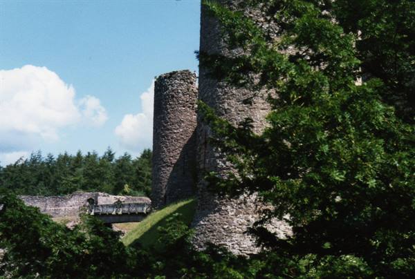 Medieval stone towers among green trees, blue sky with clouds