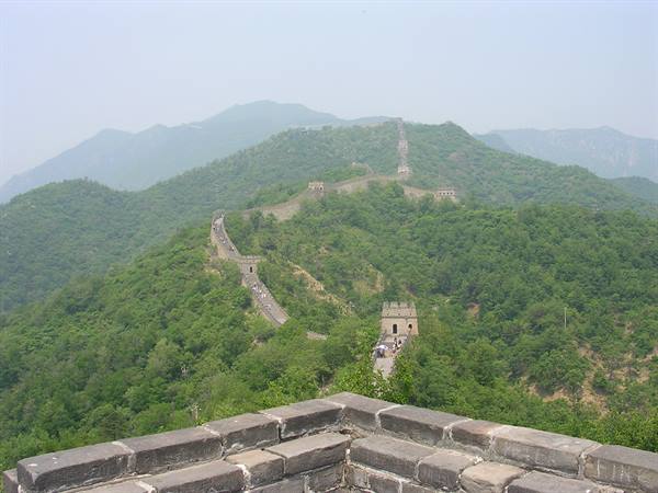 The Great Wall winds over green hills between stone towers