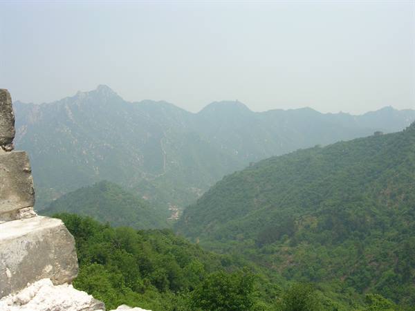 Stone wall edge over green mountains in haze, Great Wall of China