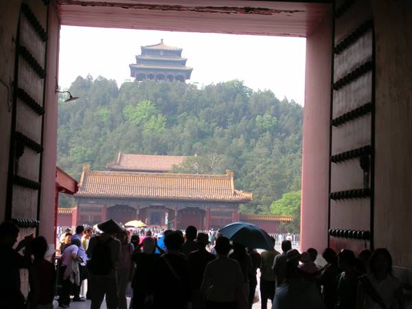 Visitors under the red gate look toward the pavilion atop Jingshan hill