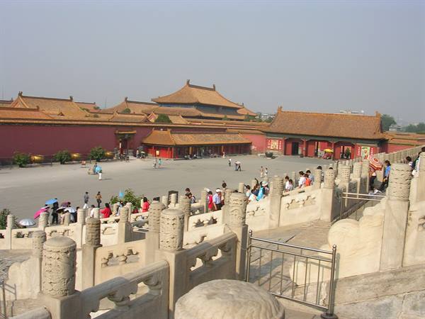 Tourists on marble staircases of the Forbidden City, golden roofs, red walls
