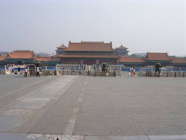 Golden roofs of Beijing's Forbidden City under hazy sky, visitors crossing the square