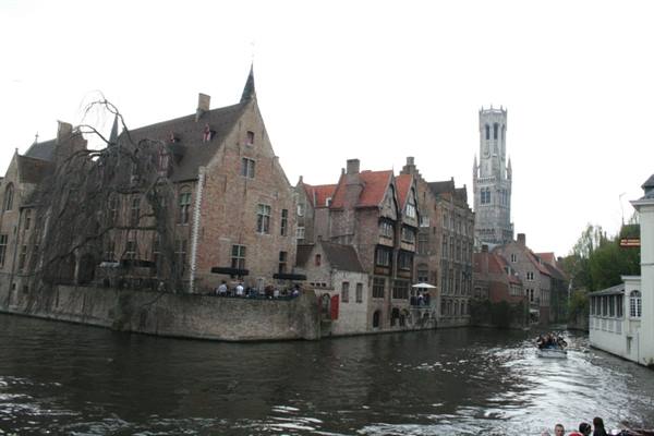 Bruges canal with brick houses, weeping willow and the Belfry tower behind