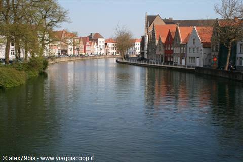 Red brick gabled houses reflect in a Bruges canal