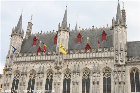 Gothic town hall of Bruges on Burg square, spires, statues and flags