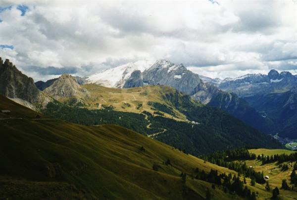 Snow-capped Marmolada above green slopes and Dolomites forests