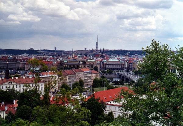 Prague red rooftops, bridge over the Vltava and TV tower under clouds