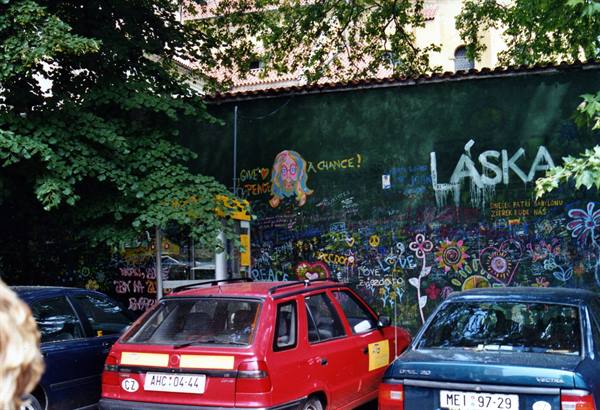 Cars parked in front of Prague's Lennon Wall, covered in colorful graffiti