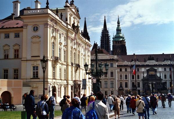 Tourists walk in front of Prague Castle with the cathedral's Gothic spires