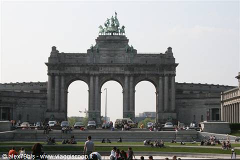 Stone triumphal arch with bronze quadriga, people relaxing on the lawn