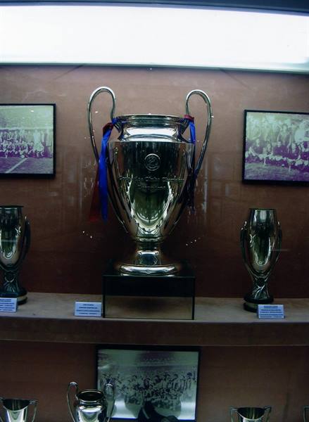 Champions League silver trophy at Camp Nou museum, surrounded by trophies and photos