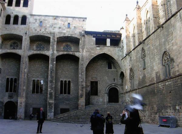 Medieval stone square with staircase and arches, tourists photographing near Barcelona City History Museum