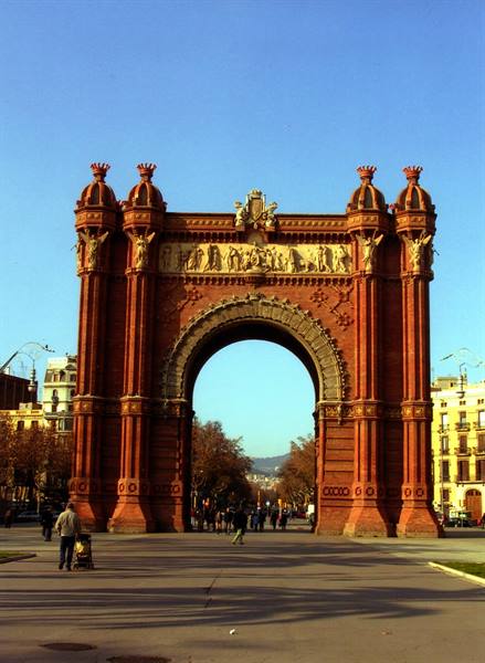 Barcelona's red brick Arc de Triomf, people strolling beneath the large arch