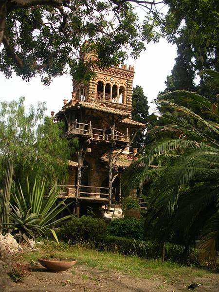 Decorated brick tower among palms and cacti in Taormina's public gardens