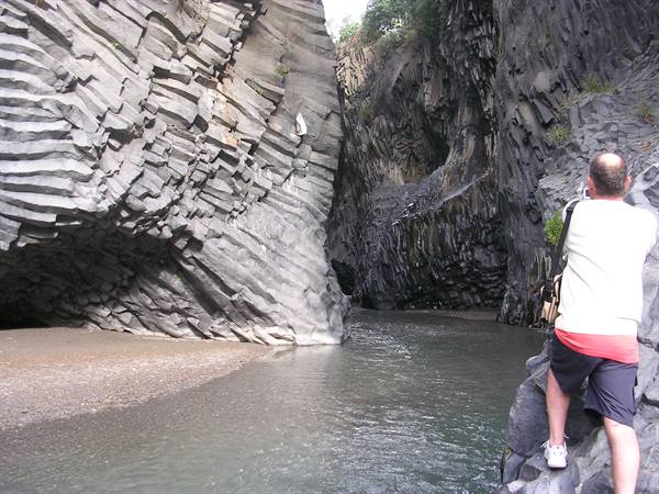 Man photographs basalt columns along the river, Alcantara Gorges