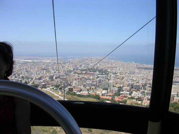 Inside the cable car cabin, cables and metal seats above the city and sea