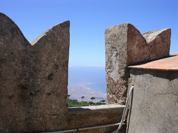 Stone battlements of a castle open onto the coastline and sea