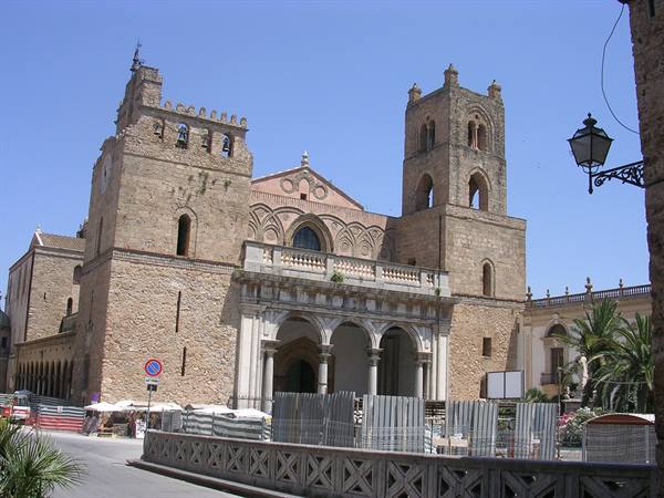Monreale Cathedral stone facade with towers, sunlight, square in foreground