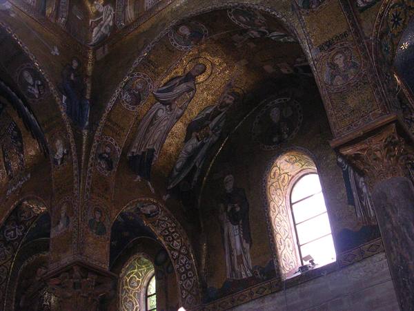 Golden Byzantine mosaics with saints on church vaults, lit windows