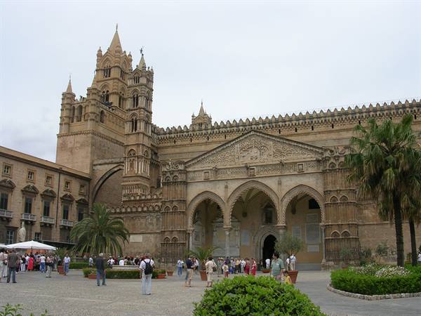 Tourists walk in front of Palermo Cathedral, light stone, overcast light, palm trees