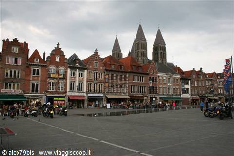 Tournai square with brick houses, cafés with motorcycles and cathedral twin towers