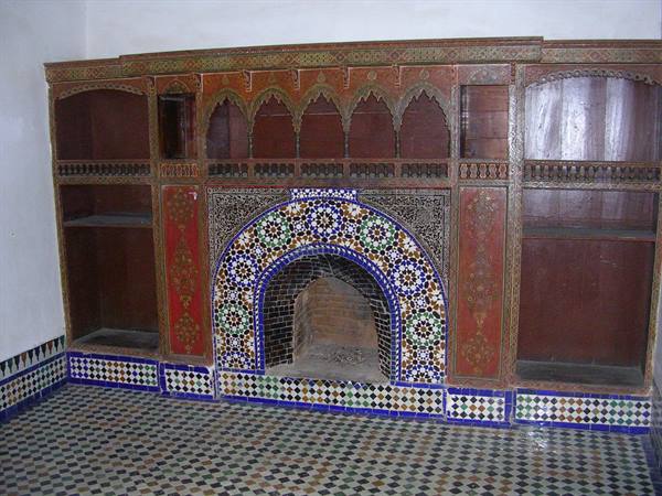 Arched fireplace decorated with colorful zellige tiles and carved cedar wood