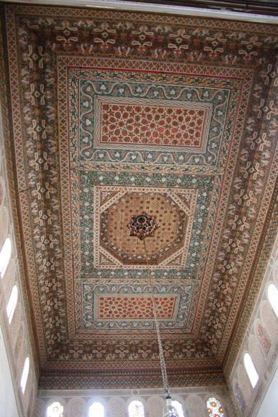 Inlaid wooden ceiling with geometric and floral patterns, lit by hanging lamps