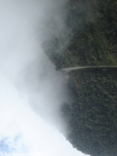 Dirt road wrapped in fog across the green mountain forest