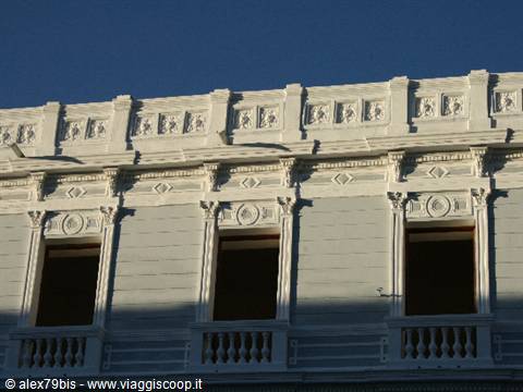 Historic facade with arched windows and white decorations under blue sky