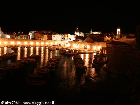 Dubrovnik old port at night: moored boats, illuminated walls and lights reflecting on water