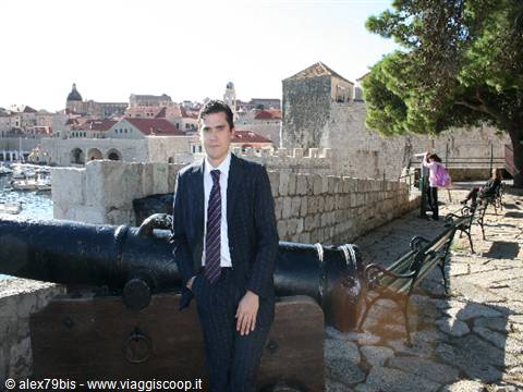 Man in suit and tie beside an old cannon on Dubrovnik walls