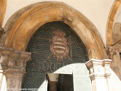 Stone portal with carved arch and coat of arms on studded wooden door