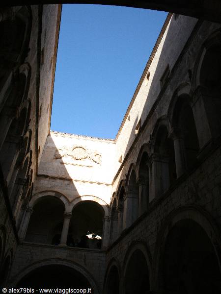 Historic palace courtyard with stone arches under a blue sky