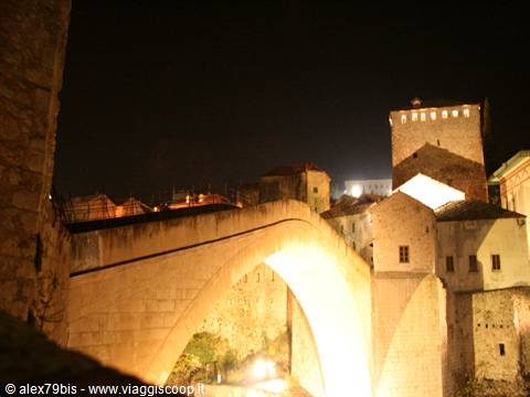 Mostar's Old Bridge illuminated at night between stone towers