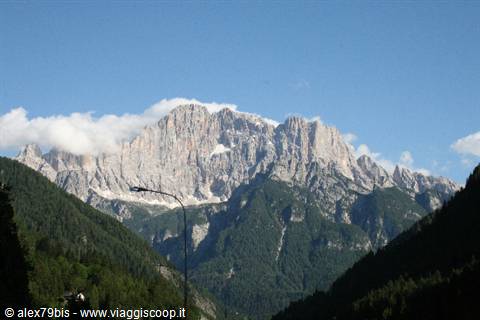 Rocky walls of Monte Civetta above green forests, street lamps in foreground