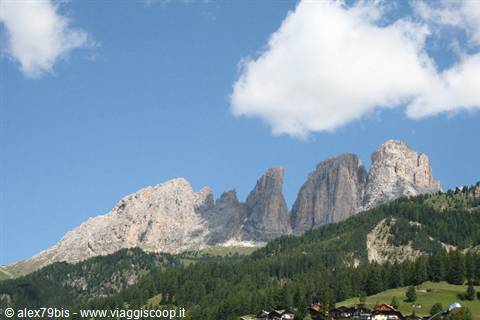 Dolomite rock towers above fir forests and wooden chalets, Sassolungo