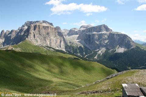 Dolomites: rocky peaks rising over green alpine meadows, stone hut, blue sky