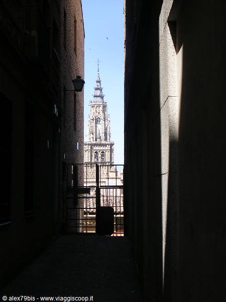 Dark alley with gate: the Gothic tower of Toledo cathedral