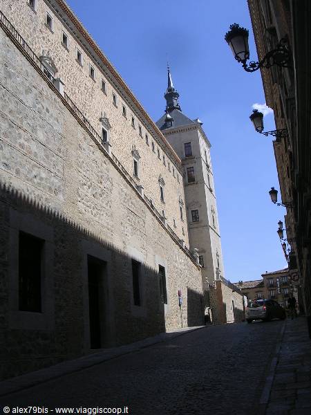 Stone walls and tower of the Alcázar of Toledo above a cobbled street