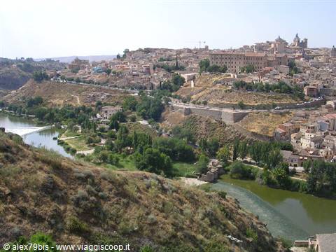 Toledo: ancient houses on hillside, Tagus river and greenery beneath blue sky